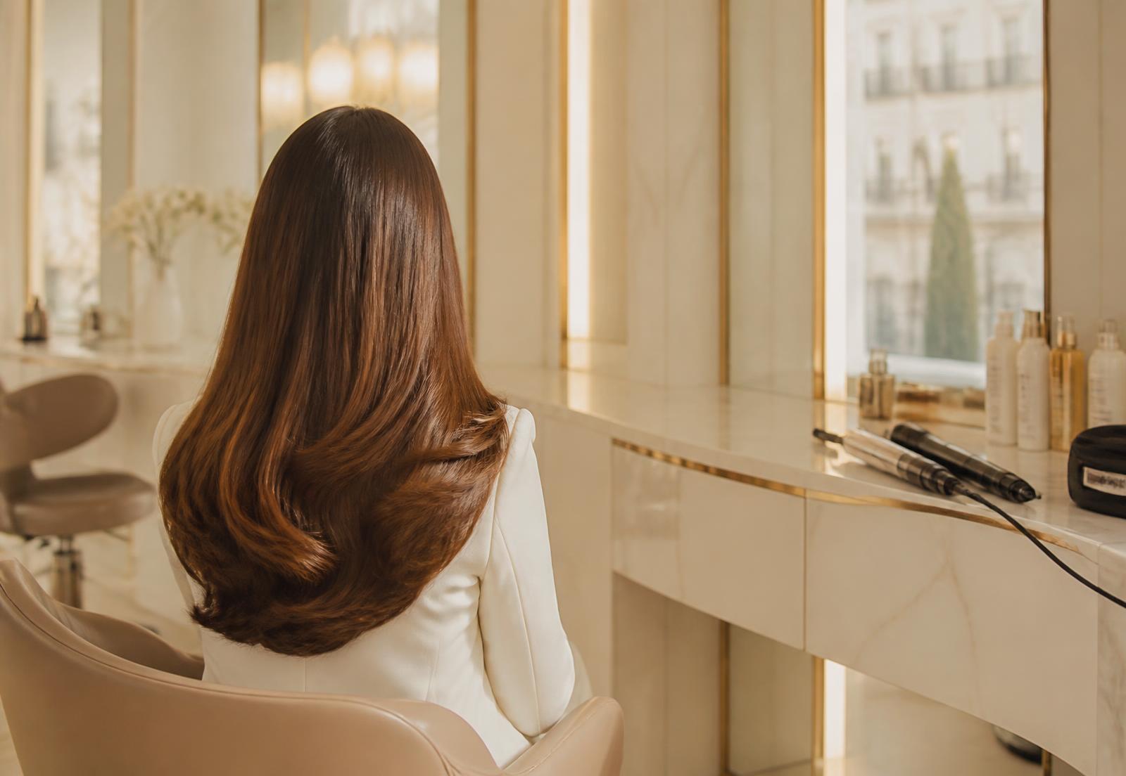 A client with a glossy blowout seated at a marble styling station in Lumière Salon